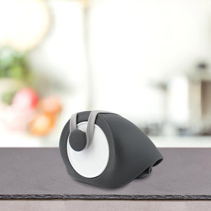 Sodoben črno-beli avtomat za trakove stoji na sivem pultu poleg PLATINUM Prenosni bidon z lijakom za pse z zamegljenim kuhinjskim ozadjem.